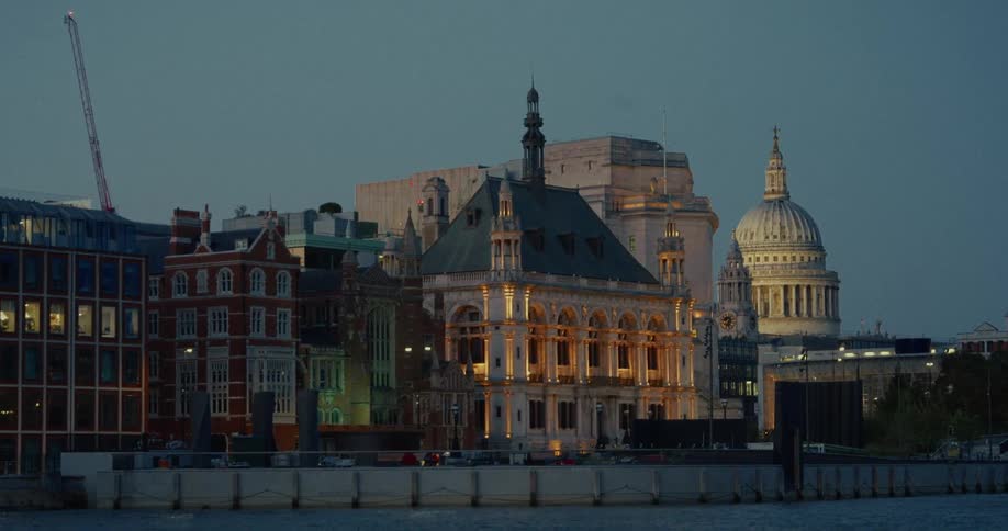 Historic buildings lit by the riverside with st pauls cathedral dome in the background