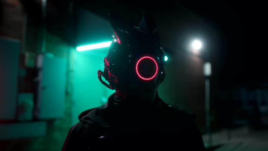 A person standing outdoors at night wearing a helmet with a circular red led light