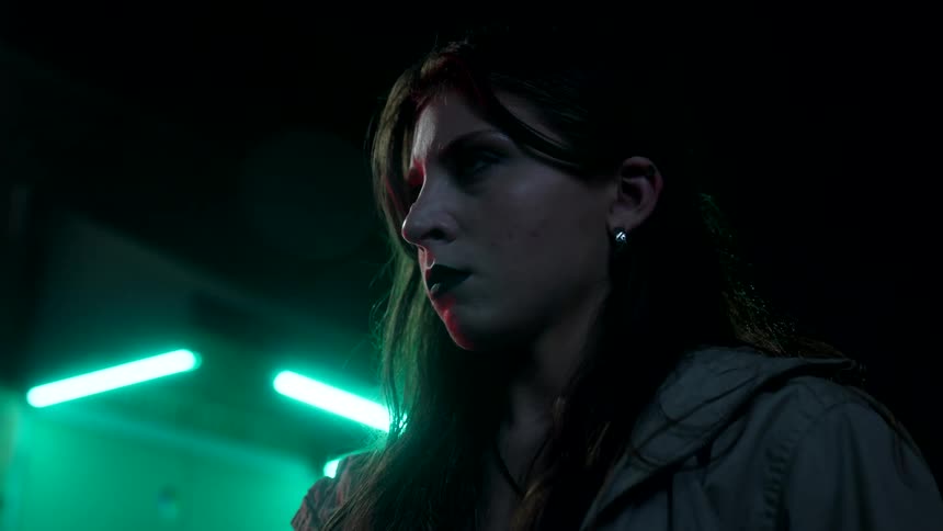 Woman with angry expression holding an object outdoors at night