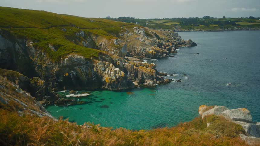 Waves crash against rocky coastal cliffs beside the turquoise ocean