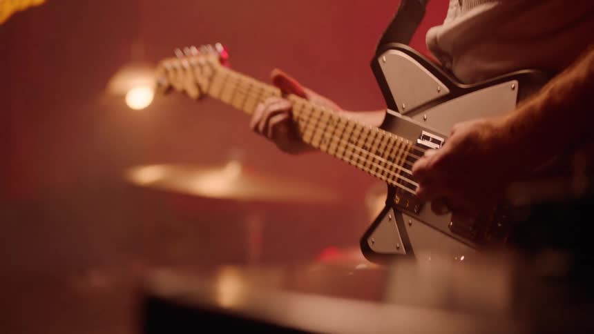 Musician plays a white electric guitar during a performance