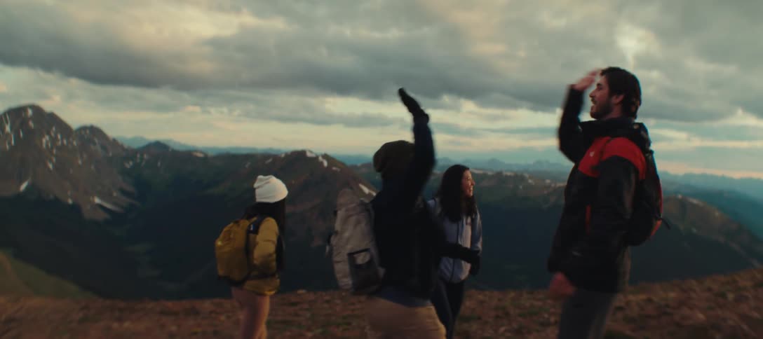 Group of four friends on a mountain celebrating together with a high five