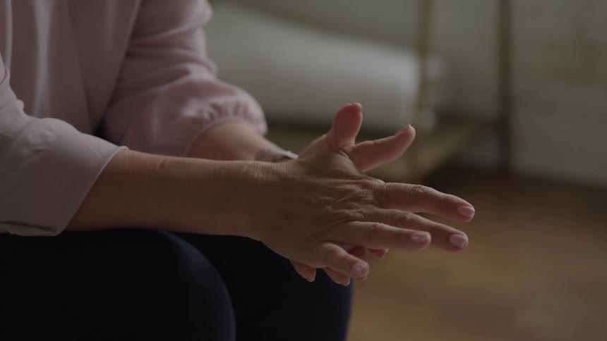 Female hands rest gently on each other in a gesture of calm