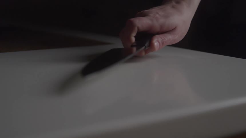 Man grasps a knife lying on the counter and picks it up