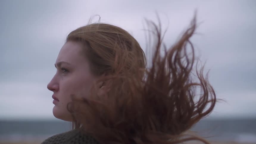 A woman's hair blows in the wind on a cloudy day