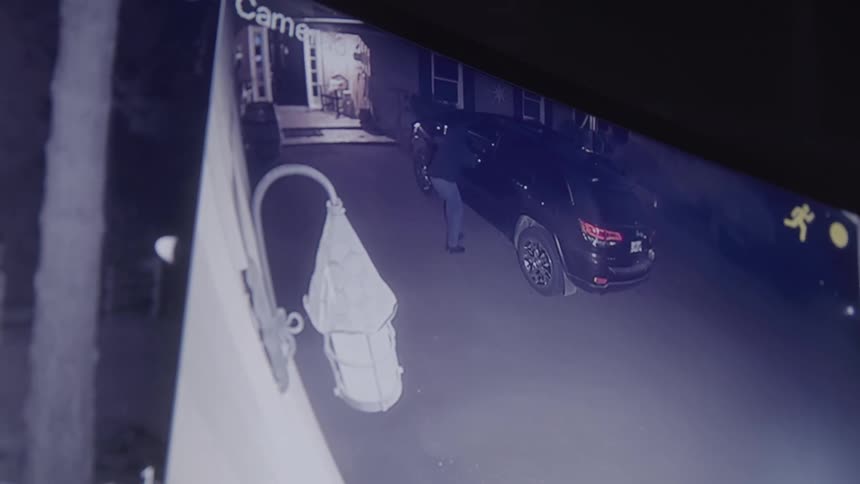 A thief breaks into a car outside a house