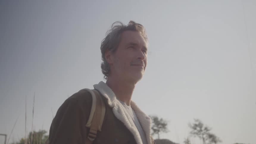 The man smiles while looking outside