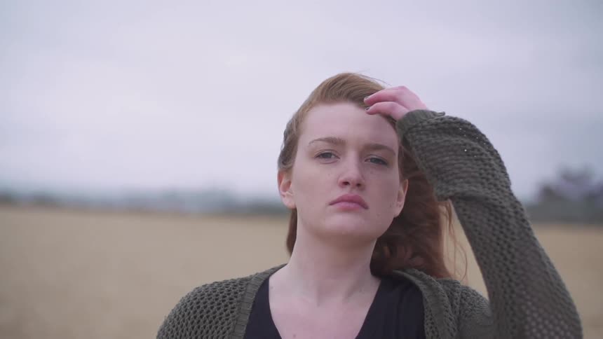 Woman brushes her hair away from her face