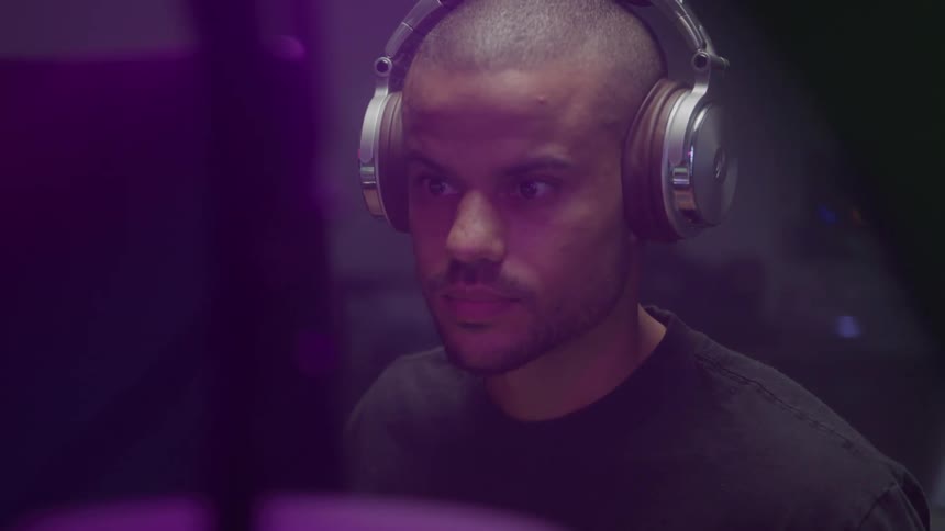 Man wearing large headphones in a studio lit by purple light
