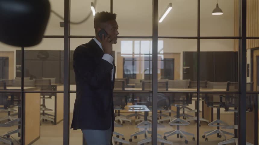 The man talks on his cell phone and walks in the office