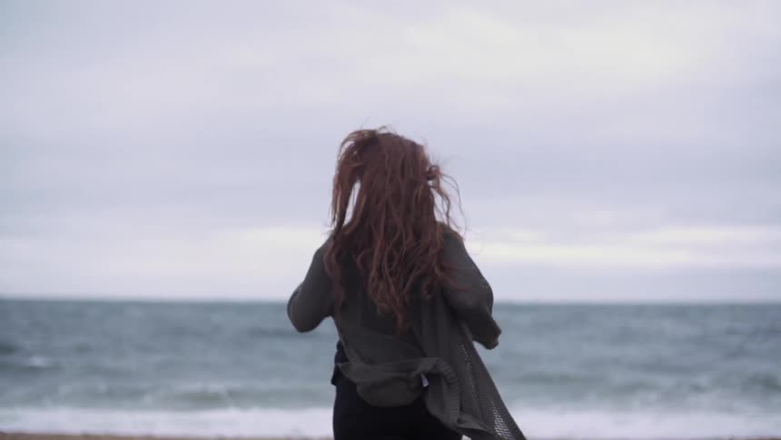 A woman runs down a beach towards the water