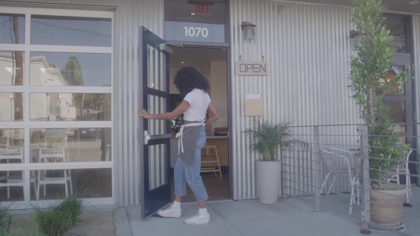 The woman opens the restaurant door