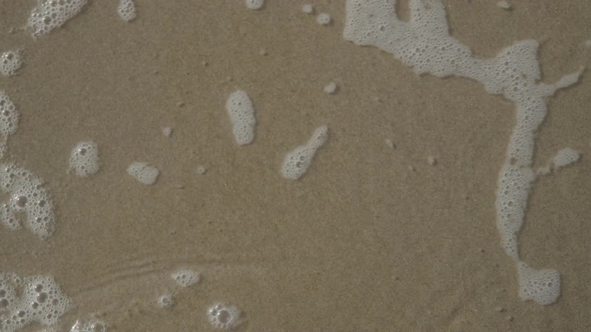 The water moves over the sand on the beach