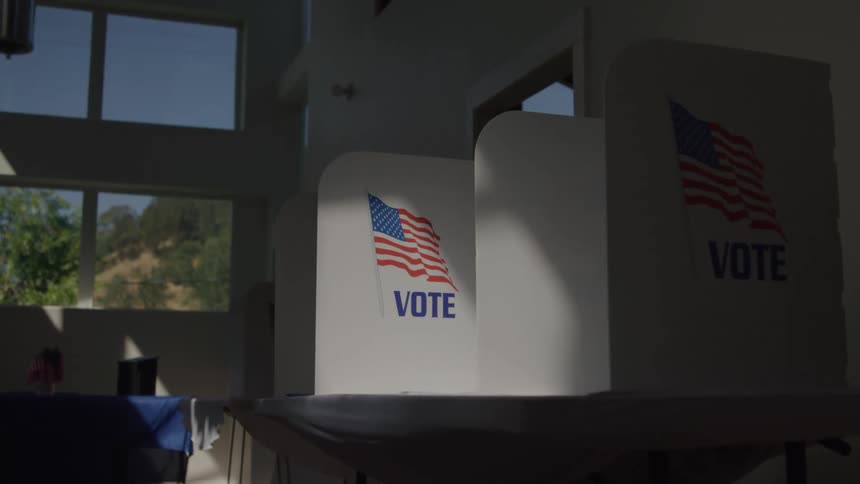Voting booths with the word vote and the united states flag displayed