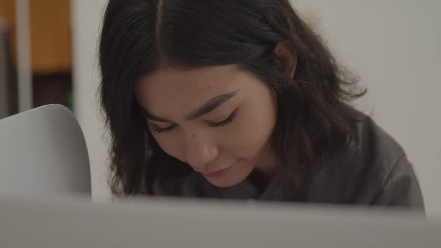 A woman with dark hair concentrates as she looks down to cast her ballot inside a private voting booth during an election