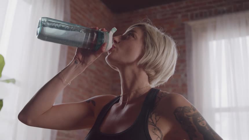 Tattooed shorthaired woman drinking water from a sports bottle