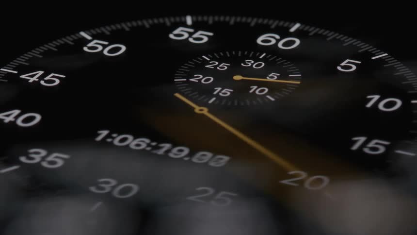 A stopwatch is in focus its second hand quickly ticking away the camera pans out to reveal that the stopwatch is on a dashboard indicating someone is timing a race or activity