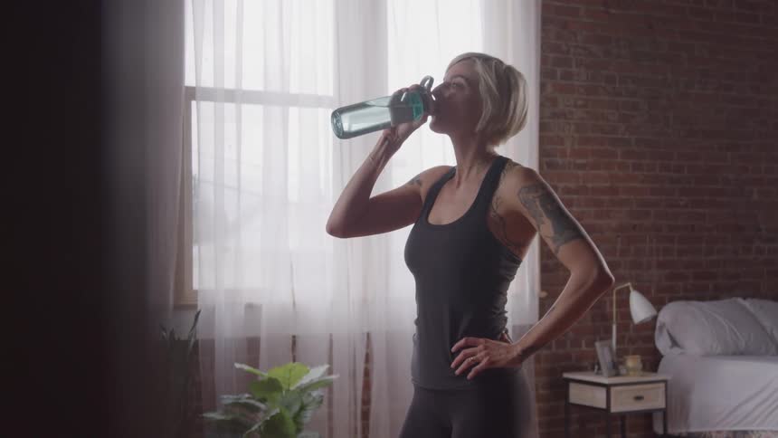 The woman drinks from her water bottle