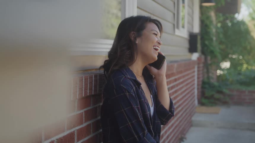 The woman laughs while talking on her cell phone