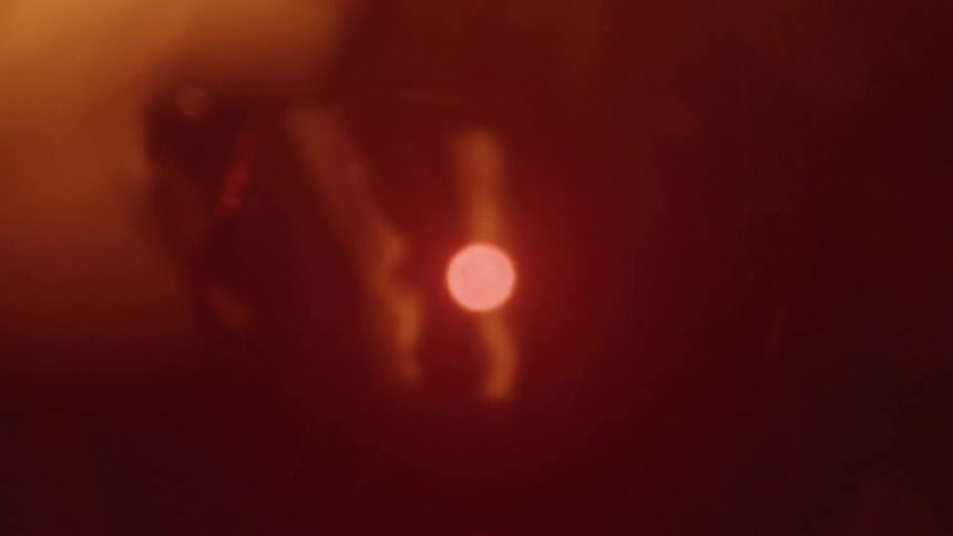 A blurred abstract shot with a dark red background shows a bright circular white light in the center of the frame as flames move around it