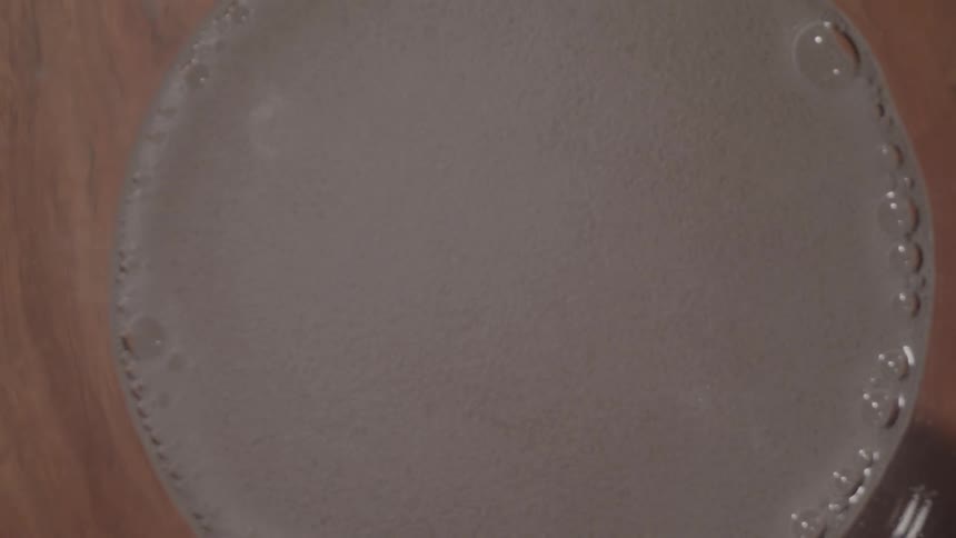 A fizzy tablet is dropped into a glass of water and it begins to dissolve the water turns cloudy as it fills with countless tiny bubbles that rise to the surface