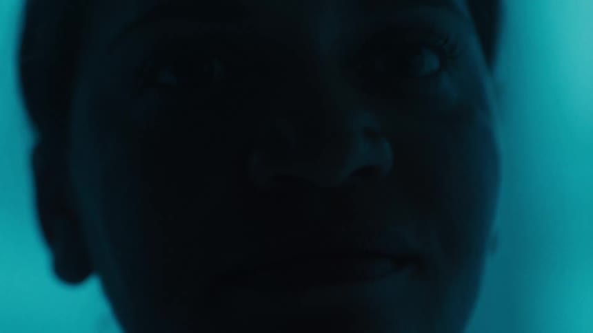 A womans face in darkness surrounded by blue light
