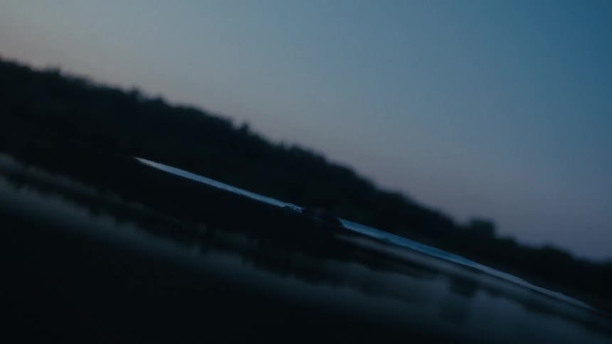Person emerges from the water at dusk with a dark silhouette against the sky