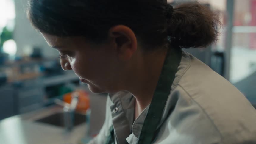 A chef looks down in concentration while working in a kitchen