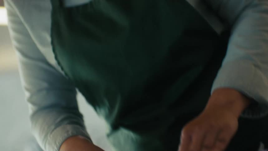 A woman in a large kitchen using a big knife to chop onions on a chopping board