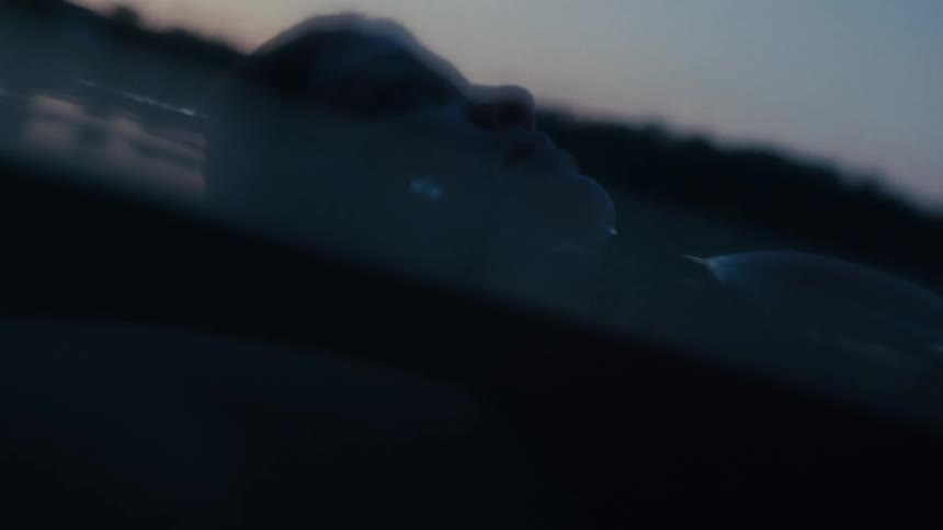 A woman floats on her back in a lake at dusk