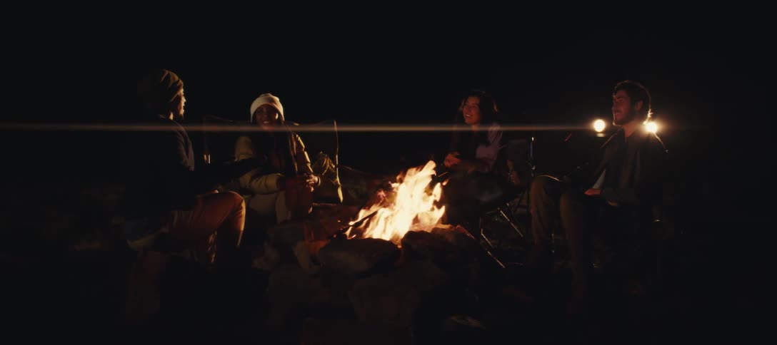 The man is talking while friends listen by the fire