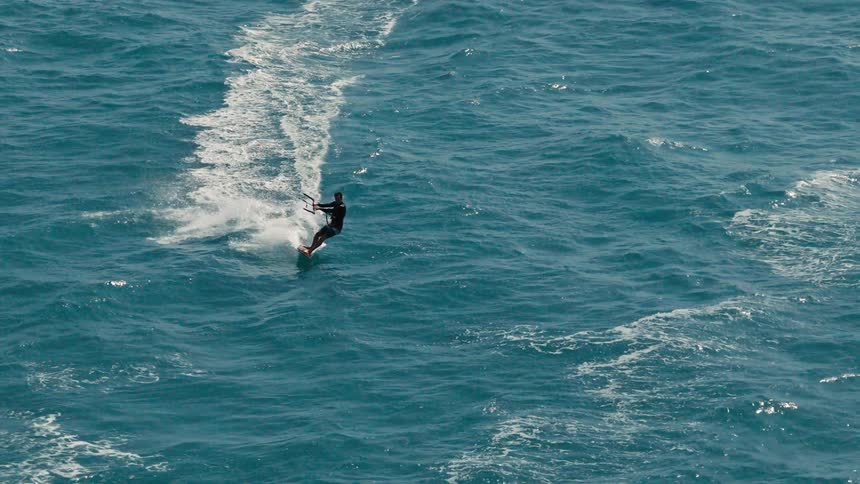 A person on a small board in the ocean holding a handle dragging them along