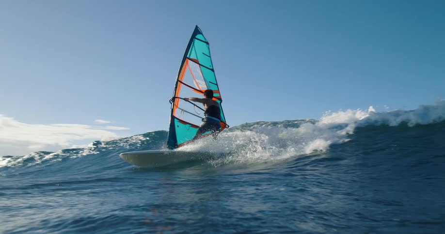The man rides a wave while windsurfing