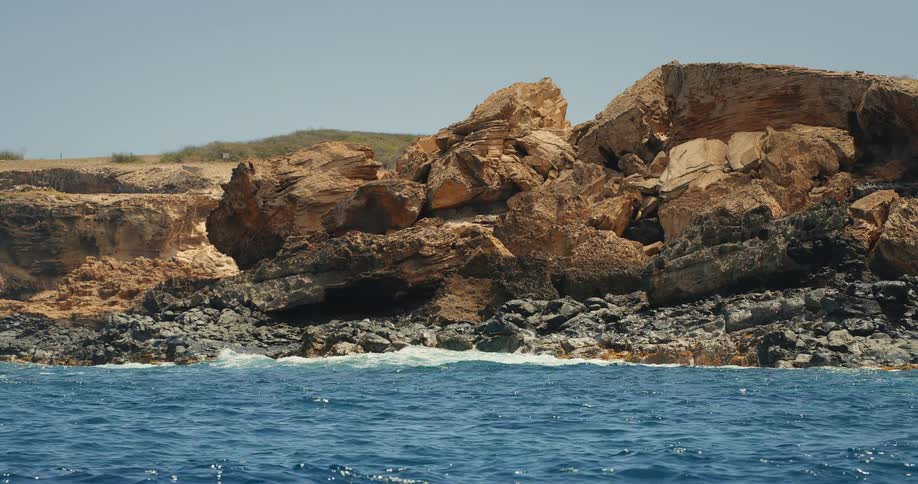 A coastline covered in large rocks with the calm sea gently hitting them