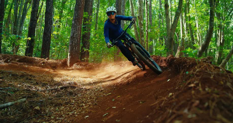 Mountain biker taking a sharp turn at high speed on a dirt trail in the forest