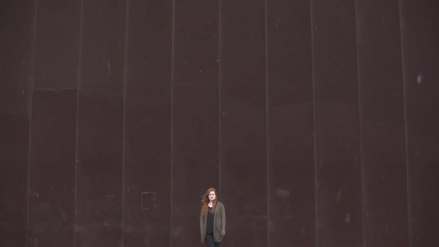 Woman standing in front of a huge brown wall