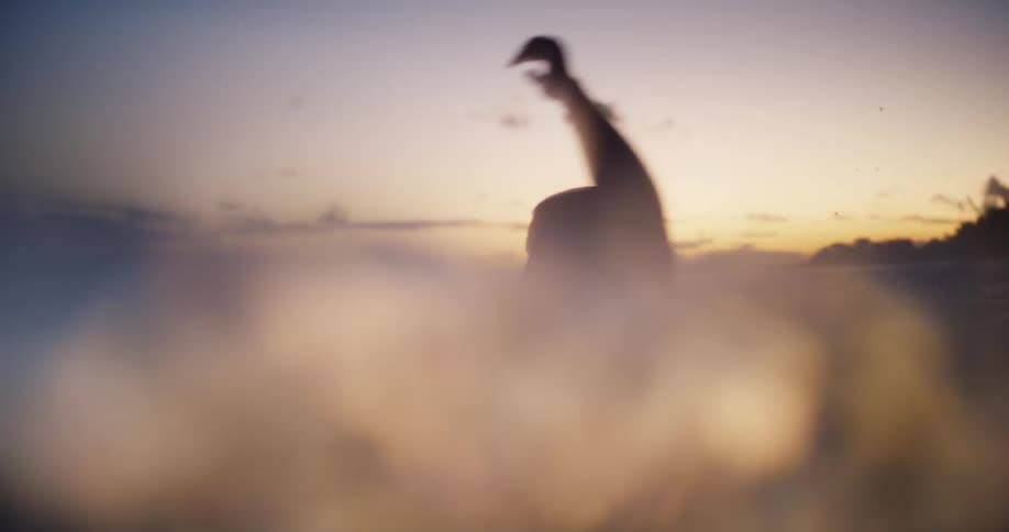 A man and a woman on a beach running into the ocean until theyre up to their necks in the sea splashing water as they move