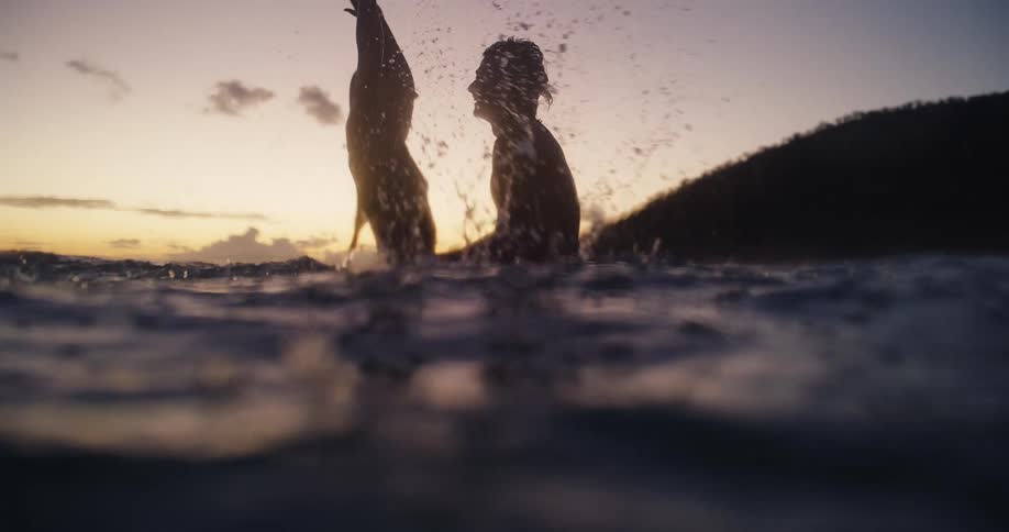 The couple splash and hug in the ocean