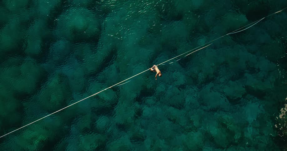 Person swims in the sea holding a rope seen from above