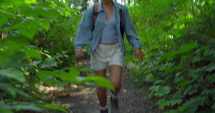 The woman is running on the trail in the forest