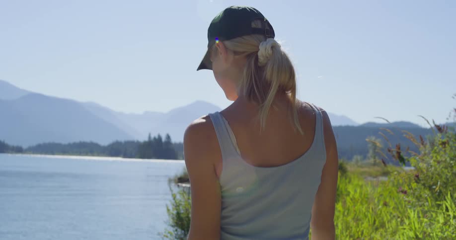 Woman wearing a cap observing the mountainous landscape by the lake