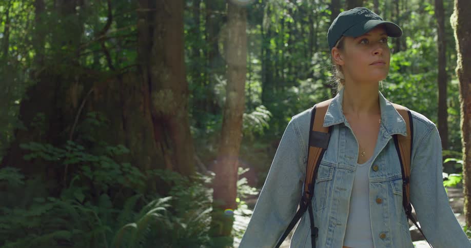 The woman is smiling as she hikes in the woods