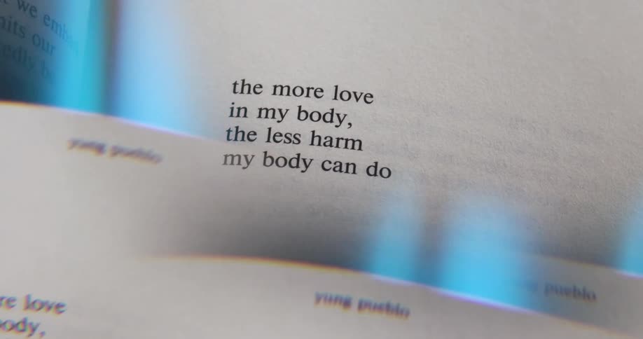 A camera focuses on a page of a book which reads the more love in my body the less harm my body can do the page is blurry at first and then comes into clear focus