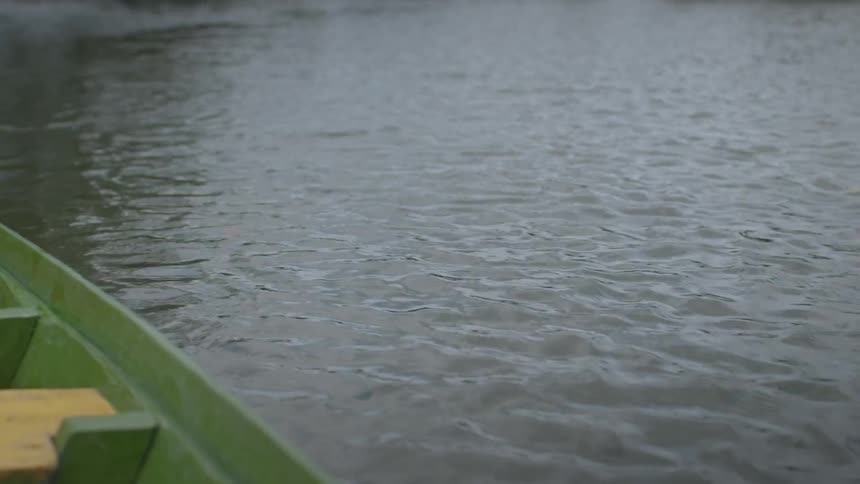 The man is rowing the boat in the large stream