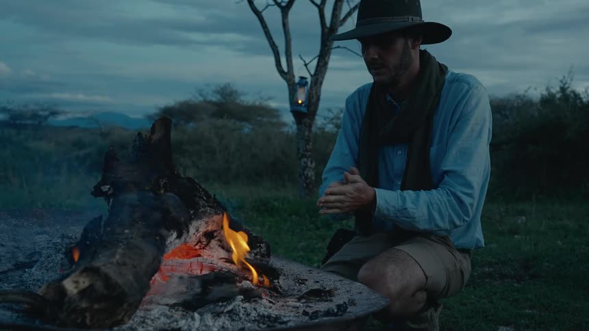 A man warms his hands by a campfire
