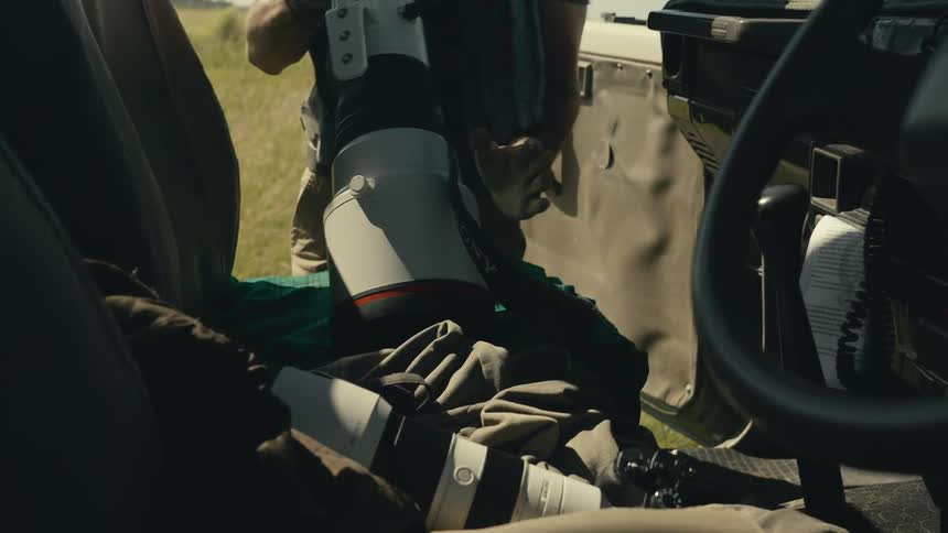 Field photographer aims a long lens from a vehicle