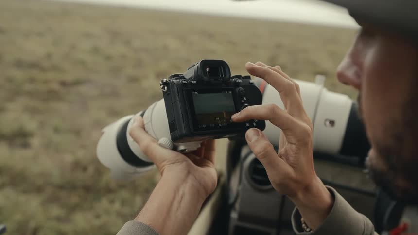 A man touching the screen of a camera where there is a picture of a cheetah