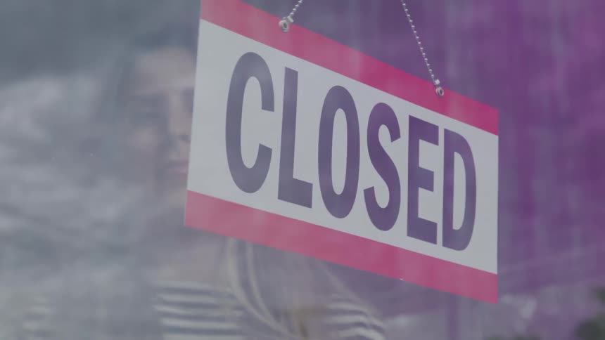 The woman turns the open sign on the shop