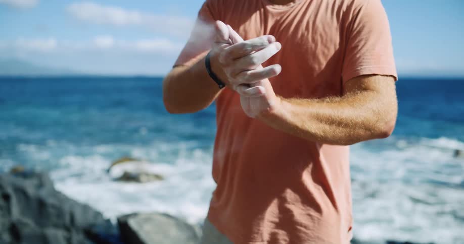 Man rubs chalk on his hands by the sea