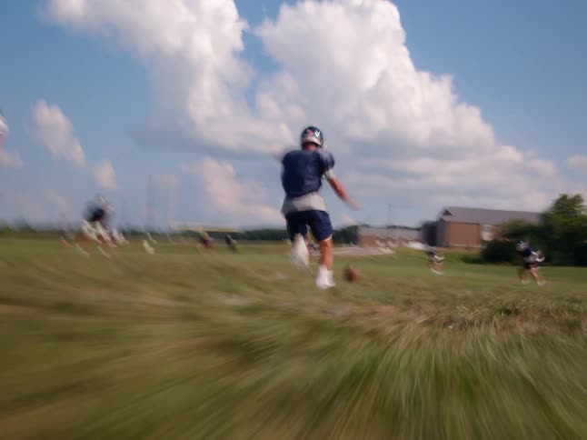 Football kicker kicks the football during practice on a grass field